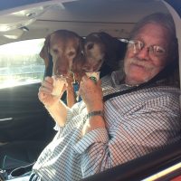 Roddy Moore seated in a car with two dogs.