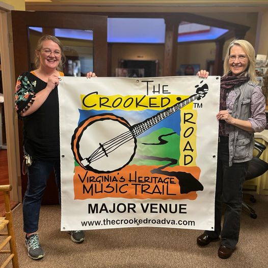 Two women holding a banner for the Crooked Road music trail.