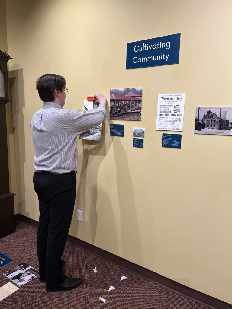 A man placing prints and photos on a wall.